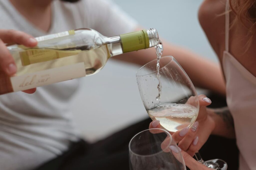 Imagem de duas mãos enchendo uma taça de vinho