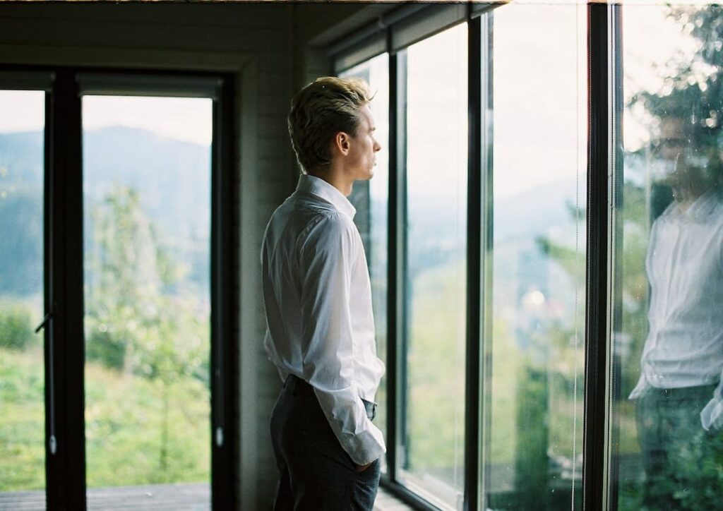 Imagem de um homem de roupa social olhando para a janela