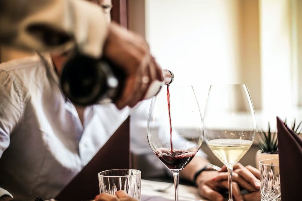 Imagem de um homem segurando a mão de uma mulher com taças de vinho na mesa