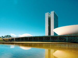 Imagem do céu azul de Brasília com prédios em uma grande praça