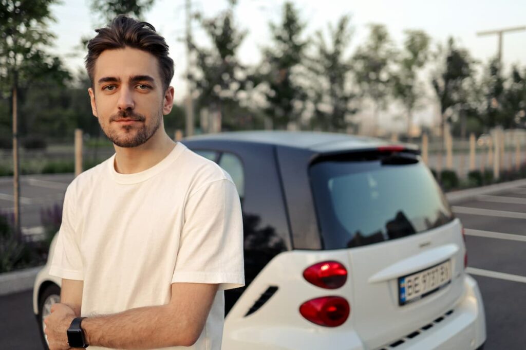 Imagem de um homem jovem na frente de um carro branco